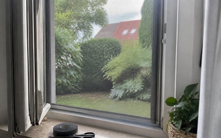 Fliegengitter im Aluminiumrahmen an einem geöffneten Fenster