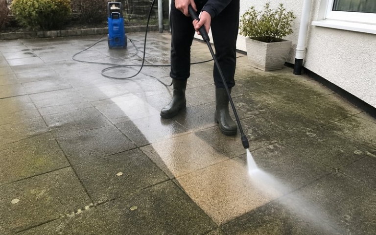 Hochdruckreiniger reinigt Betonplatten auf einer Terrasse